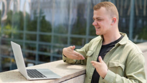 Man using ASL to speak with someone on his laptop.